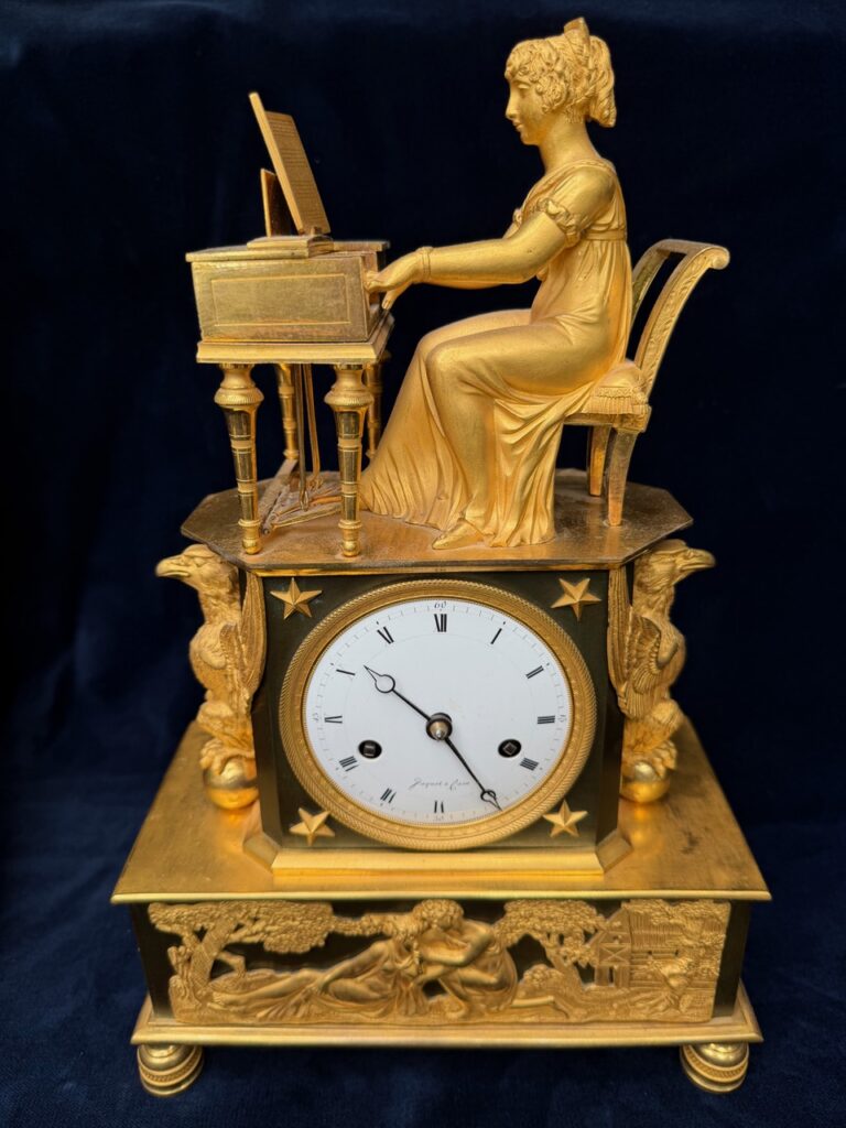Empire pendule met dame aan een tafelpiano, verguld brons